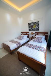two beds in a room with white walls at Lakeside Serenity Stylish 2BR Getaway - Entebbe in Entebbe