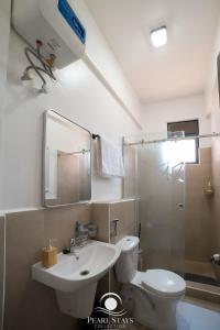 a bathroom with a toilet and a sink and a shower at Lakeside Serenity Stylish 2BR Getaway - Entebbe in Entebbe