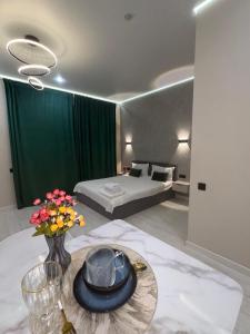 ein Hotelzimmer mit einem Bett und einem Tisch mit Blumen in der Unterkunft Comfort Studio Apartment in Almaty