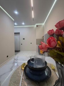 ein Zimmer mit einem Tisch, auf dem ein Teller und rote Rosen stehen in der Unterkunft Comfort Studio Apartment in Almaty