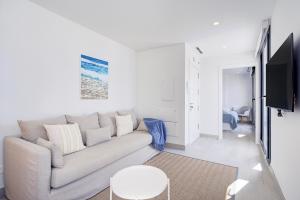 a white living room with a couch and a tv at Casa Vega, a un minuto de la playa, PARKING included in Estepona