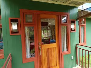 a green house with a wooden door and windows at Casa Hermosa FAM in Santa María