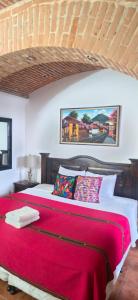 a bedroom with a large bed with a red blanket at Casa Santiago Son 2 in Antigua Guatemala
