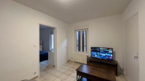 a living room with a flat screen tv and a table at logis des abeilles sejour-tricastin in Pierrelatte