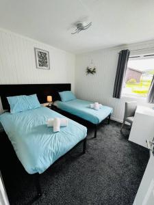a bedroom with two beds with blue sheets and a window at Tigh Na Mara in Dunoon
