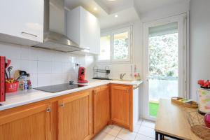 a kitchen with wooden cabinets and a sink and a window at Les jardins de Rangueil, Parking, Métro, Piscine in Toulouse