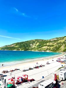 Una playa con un grupo de personas y el océano. en Loft Prainha - VISTA MAR, en Arraial do Cabo