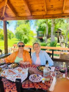 dos mujeres sentadas en una mesa con comida en Hosteria Zafiro, en Tigre
