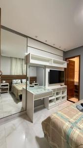 a bedroom with two beds and a desk with a television at Conforto & Sofisticação in Macapá