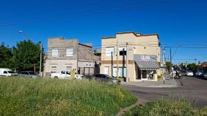 a building on a street with cars parked in a parking lot at Departamentos céntricos con parrilla in Punta Alta