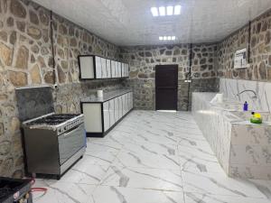 a kitchen with a stove and a stone wall at استرحه ام الحمام in Suḩaybah