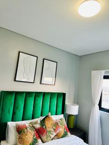 a bedroom with a green headboard with fruits on it at Merensky Tower Apartment in Windhoek +2 photos