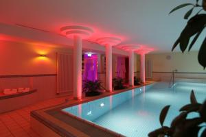 ein Swimmingpool mit rosa Beleuchtung in einem Gebäude in der Unterkunft Hotel Sonnenblick Bebra in Bebra