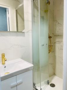 a bathroom with a glass shower and a sink at Bright apartment Disneyland Paris Wi-Fi in Lagny
