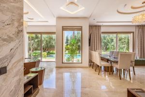 マラケシュにあるVilla Kamélia 5000m Hammam Piscine Chauffée et Sans Vis à Visのテーブルと椅子と窓のあるダイニングルーム