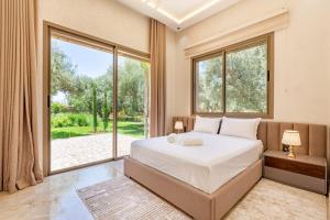 マラケシュにあるVilla Kamélia 5000m Hammam Piscine Chauffée et Sans Vis à Visの大きなベッドと大きな窓のある寝室 +39枚の写真