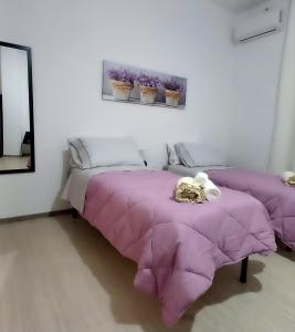 two beds in a room with purple blankets at S'apposentu 'e Santa Ruche in Oniferi