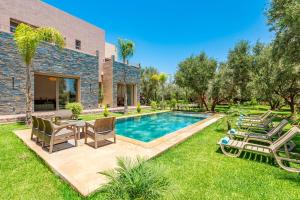 マラケシュにあるVilla Kamélia 5000m Hammam Piscine Chauffée et Sans Vis à Visの裏庭(椅子とテーブル付きのプールあり)