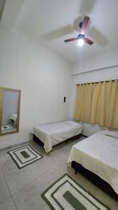 ein Schlafzimmer mit zwei Betten und einem Deckenventilator in der Unterkunft Cantinho da Vovó in Aparecida
