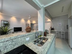 a kitchen with a sink and a counter top at Ap Pitangueiras - 3 suítes - Pé na Areia - Ao lado do Shopping in Guarujá +6 photos