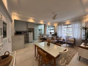 a kitchen and living room with a table and chairs at Ap Pitangueiras - 3 suítes - Pé na Areia - Ao lado do Shopping in Guarujá
