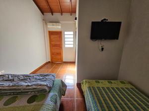 a room with two beds and a television on the wall at MH Hostel in Encarnación