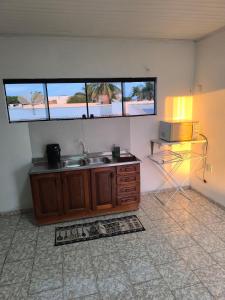 a kitchen with a sink and two windows at Apartamento Central in Primavera do Leste