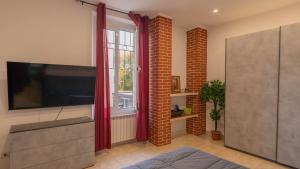 a living room with a tv and a brick wall at Appartamento don orione in Tortona +6 photos