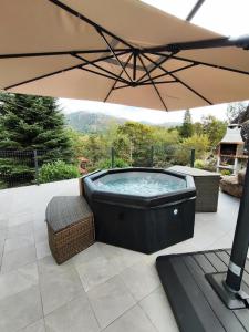 a hot tub sitting under an umbrella on a patio at Casa Montanha in Campo do Gerês
