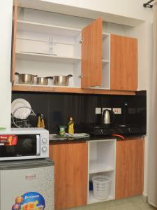eine Küche mit Holzschränken und einer Mikrowelle in der Unterkunft Havenly Homes Stay in Gatunga