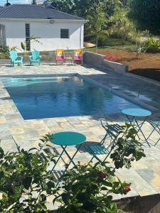 two tables and chairs next to a swimming pool at Coco-orchidées Le Domaine Mannou in Sainte-Rose