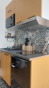 a kitchen with a black and white tile wall at Le Réverbère, appartement de vacances in Lectoure