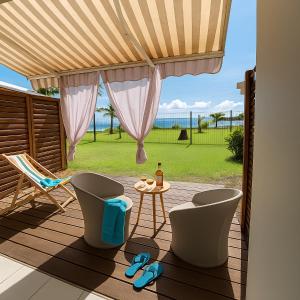 a patio with a table and chairs and a view of the ocean at Studio le Colibri, Entre terre et mer, vue incroyable, citerne in Le Gosier +6 photos