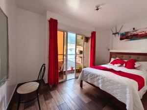 a bedroom with a bed with red curtains and a window at Casa Gaviota Dorada in Baños