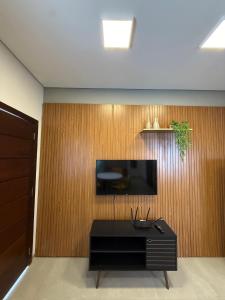 a living room with a tv on a wooden wall at Loft com 2 Qts e garagem em área nobre in Sinop +7 photos