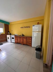 a kitchen with yellow walls and a white refrigerator at Paihuen in Plottier +2 photos