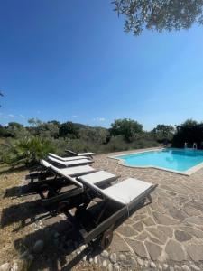 a group of lounge chairs next to a swimming pool at La Casa del Mandorlo in Posticciola