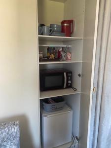 a kitchen pantry with a microwave and a refrigerator at Carpenters-stay in Dorking