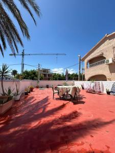 a patio with a table and chairs on a red floor at Apartamento Isabel in Denia