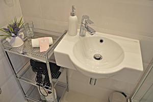 ジェロナ・グラにあるApartament Greyのバスルーム(白い洗面台、棚付)