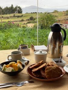 a table with a plate of food and a tea kettle at Titicaca Lodge Amantani in Amantani