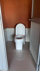 a bathroom with a white toilet in an orange wall at Titicaca Lodge Amantani in Amantani