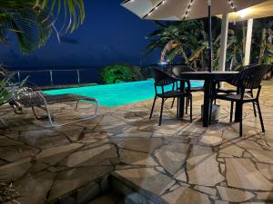 Black RockにあるBirdies Nest Upper 2 Bedroom Beach Viewのプールサイドのテーブル(椅子付)とパラソル付