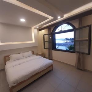 a bedroom with a bed and a large window at منتجع تالابيه العقبة in Aqaba