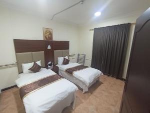 Al Muḩassinにあるالعييري للشقق المخدومة الاحساء 4のベッドが2つと窓があるホテルの部屋