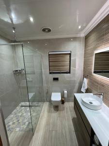 a bathroom with a toilet and a shower and a sink at Pillowtalk guest house your home away from home in Middelburg +26 photos