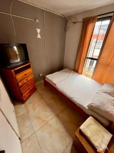 a small bedroom with a bed and a tv at Hotel El Progreso - Económico, Central y Familiar en Armenia in Armenia