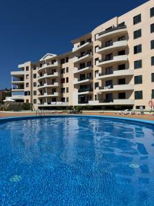 a large swimming pool in front of a building at Garajau Madeira Holidays in Caniço