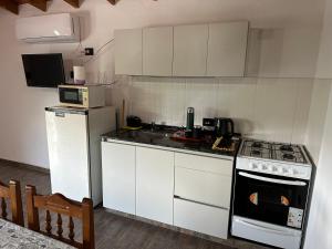 une cuisine avec des armoires blanches et un four à plaques de cuisson dans l'établissement El Paisaje, à Cuesta Blanca