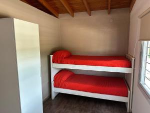 une petite chambre avec deux lits superposés avec des draps rouges dans l'établissement El Paisaje, à Cuesta Blanca